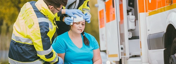 Two medical professionals placing towels on a woman's head to help clean up her head from a head injury.