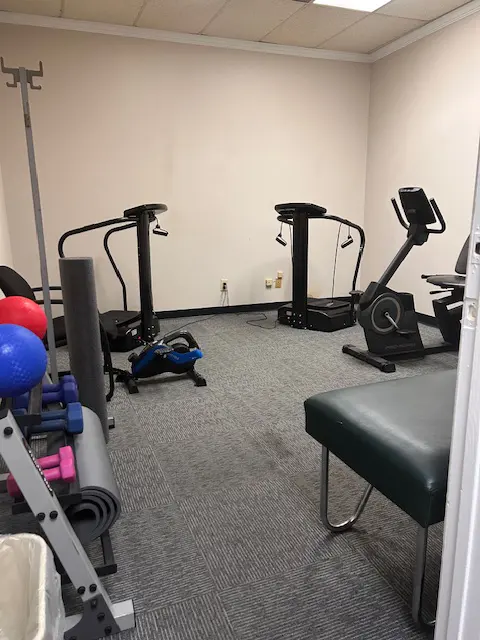 A room with physical therapy equipment, weights, and stationary bike