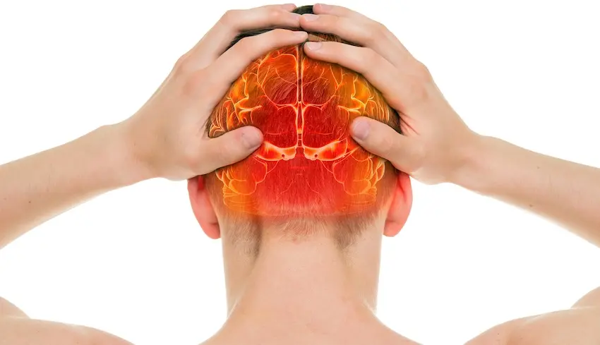 A rear view of a person pressing both hands against their skull with a vivid medical illustration overlay showing inflamed and damaged brain tissue glowing red and orange beneath the skin depicting the kind of serious hidden injuries such as traumatic brain injury that can go undetected immediately following a car accident in Georgia.