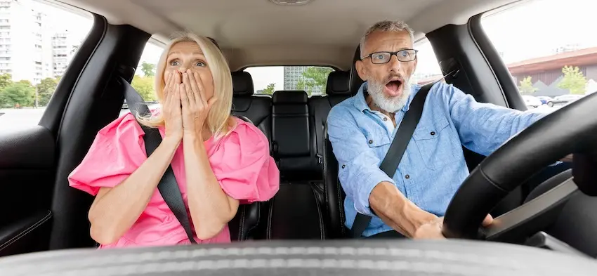 An older couple reacts with shock and horror while seated and belted inside a moving vehicle capturing the terrifying split-second moment before impact that commonly results in a car accident and whiplash injuries for both the driver and passenger in Georgia.