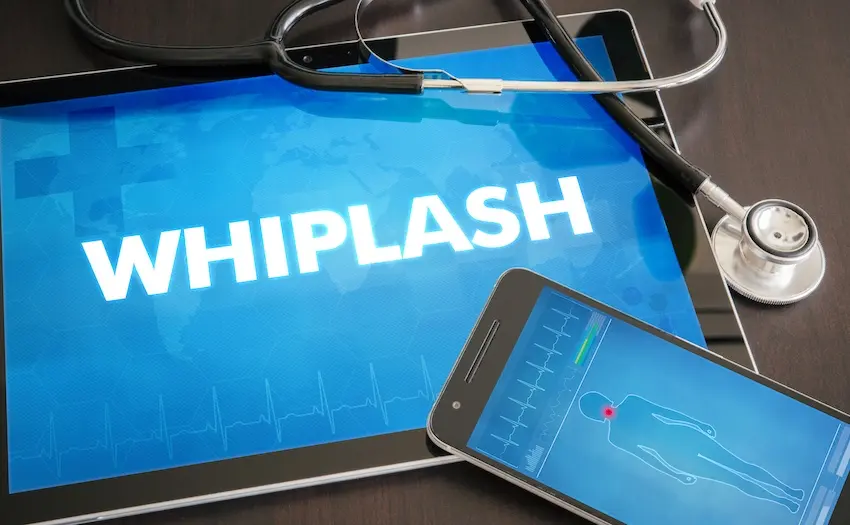 A tablet displaying the word "Whiplash" in bold white letters over a blue medical background sits alongside a stethoscope and a smartphone showing a body diagram with an injury indicator providing a clear visual reference for the medical diagnosis associated with a car accident and help from 1800hurt911ga.com in Georgia.