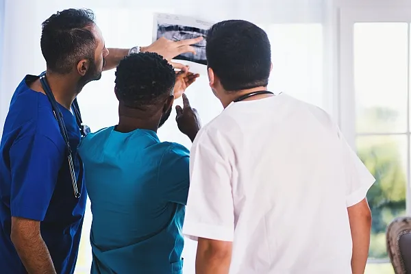 Two doctor reviewing the x ray images with a patient to show what they see in the scans.